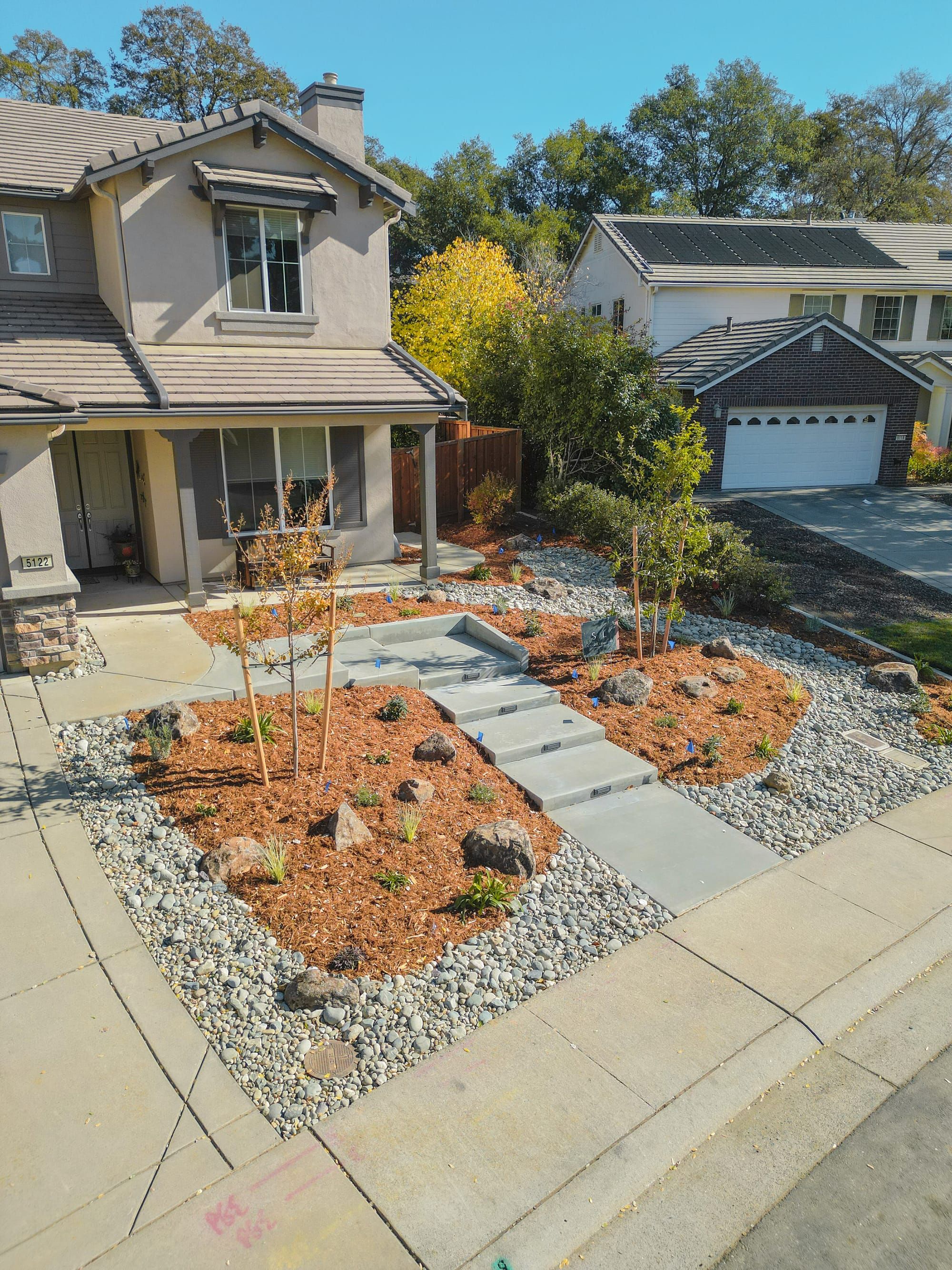Front yard with decorative mulch, concrete steps, and river rock in Sacramento