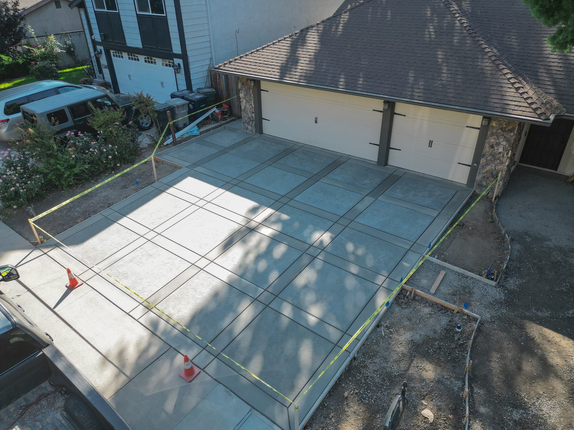 Aerial view of fresh concrete driveway pour with scored joints curing at a Sacramento home