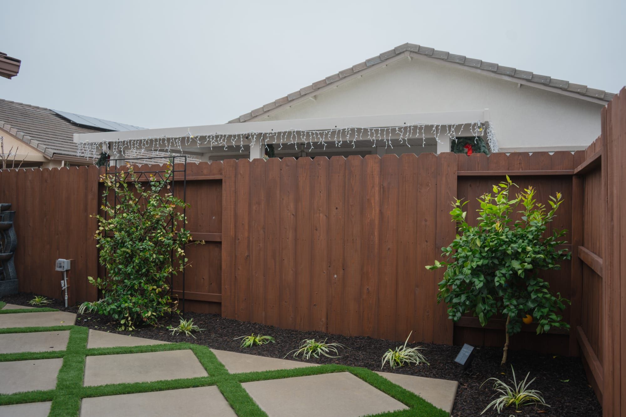 Backyard landscape with concrete pavers, artificial turf, mulch beds, and plantings in Sacramento