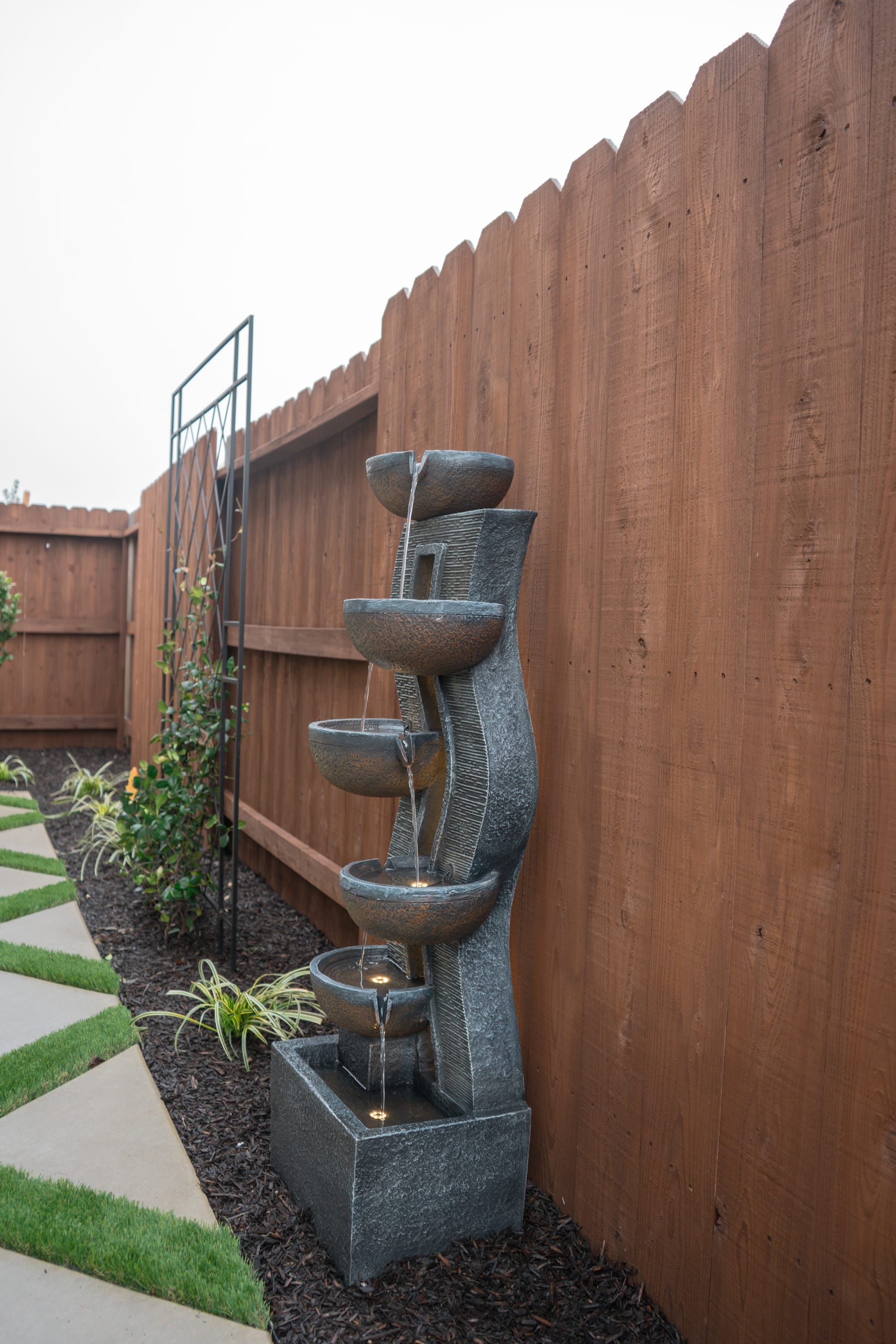 Cascading water feature with LED lighting installed along cedar fence in Sacramento backyard