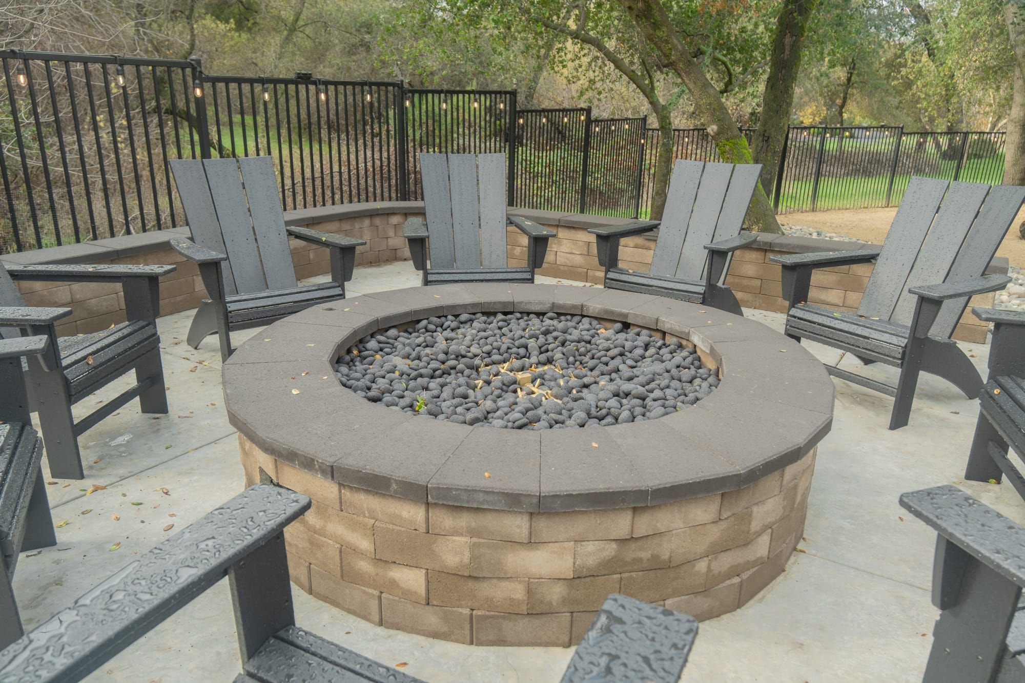 Custom fire pit with Adirondack seating and string lights in Sacramento backyard